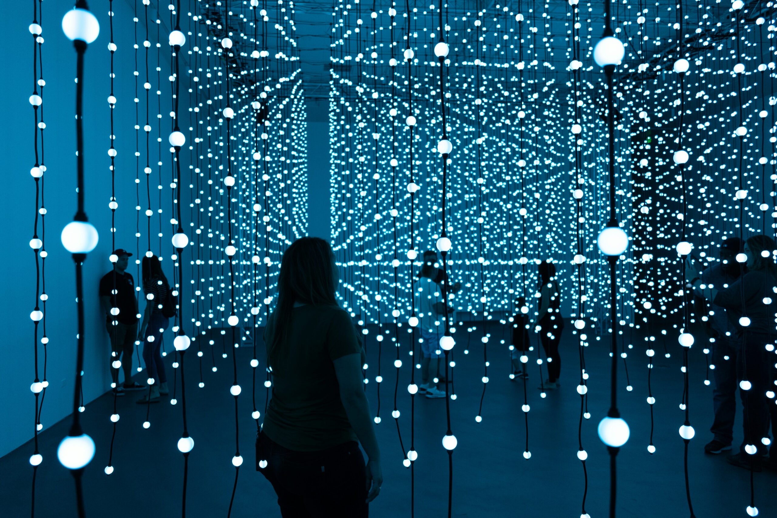 Person looking at hanging blue LED lights in an art installation